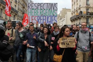 Demonstrators hold a sign reading "Let's respect and accommodate refugees" during a protest against the evacuation of migrants from a camp under a subway bridge in northern Paris on June 9, 2015. More than 350 refugees, most of them from Sudan, but also from Eritrea, Somalia and Egypt, had been living in the makeshift camp below the metro tracks between the stations of La Chapelle and Barbes-Rochechouart in the north of the French capital. AFP PHOTO / ROBIN BRAQUET